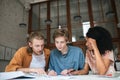 Young people working in office. Two boys with blond hair and girl with dark curly hair sitting and studying together in