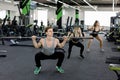 Young people working out with barbells at gym. Attractive women and handsome muscular man trainer are training in light Royalty Free Stock Photo