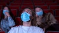 Young peoplein medical masks laughing at cinema theater. Media. Joyful Cheerful audience watching amusing comedy in