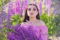 Young perfect woman with vivid purple lupin flowers outdoors