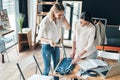 Young perfectionists. Top view of beautiful young women measuring jeans with tape and smiling while spending time in the workshop Royalty Free Stock Photo