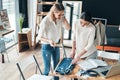 Young perfectionists. Top view of beautiful young women measuring jeans with tape and smiling while spending time in the workshop