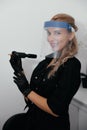 Young permanent makeup master in protection mask and black gloves with pencil in hands in beauty salon.