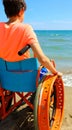 Young perosn on a wheelchair looks at the sea