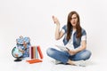 Young perplexed woman student in glasses spreading hands holding pencil and notebook sitting near globe backpack books Royalty Free Stock Photo