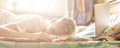 Young person lying and sleeping on the bed in the sunny morning after working on laptop in the night f Royalty Free Stock Photo