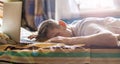 Young person lying and sleeping on the bed in the sunny morning after working on laptop in the night f Royalty Free Stock Photo