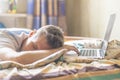 Young person lying and sleeping on the bed in the sunny morning after working on laptop in the night f Royalty Free Stock Photo