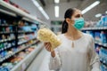 Young person with protective face mask buying groceries/supplies in the supermarket.Preparation for a pandemic quarantine