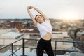 Young person raising hands in stretches on city background