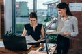 Young personal assistant discussing plans with boss in her office