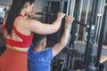 Young personal trainer helps to client on gym station back view Royalty Free Stock Photo