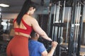 Young personal trainer helps to client on gym station pulling down the bar Royalty Free Stock Photo