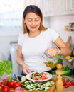 Young peruvian housewoman add oil to salad vegetable