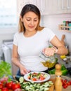 Young peruvian housewoman add oil to salad vegetable