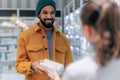 Young pharmacist helping customer to choos medication.