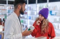 Young pharmacist helping customer to choos medication.