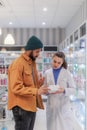 Young pharmacist helping customer to choos medication.