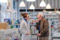 Young pharmacist helping senior man to choos medication.