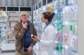 Young pharmacist helping senior man to choos medication.