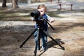 Young photographer child taking photos with camera on a tripod Royalty Free Stock Photo