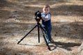 Young photographer child taking photos with camera on a tripod Royalty Free Stock Photo