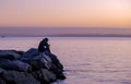 Young photographer from a cliff takes photos the sunset