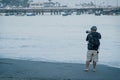 Young photographer with his professional camera taking pictures of boats in the sea