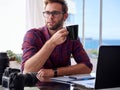 Young photographer holding coffee at his work desk Royalty Free Stock Photo