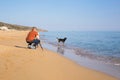 Young photographer and videographer making photos and videos of sea and his dog with the camera on a tripod Royalty Free Stock Photo
