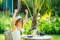 Young photographer woman feeling happy becouse she get money online while sitting at tropical cafe