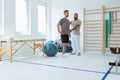 Physiotherapist exercises in a bright medical office with his injured patient