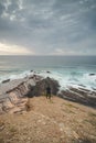 Young pilgrim stands on top of a cliff and watches the Atlantic Ocean. Praia da Amoreira near the town of Aljezur in the Odemira