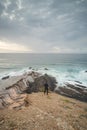 Young pilgrim stands on top of a cliff and watches the Atlantic Ocean. Praia da Amoreira near the town of Aljezur in the Odemira