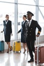 young pilot and stewardesses with luggage walking Royalty Free Stock Photo