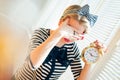 Young pinup woman showing alarm clock and hiding face