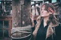 A young pirate woman with a dirty face stands near a wooden ship`s mast