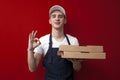 Young pizza delivery man holds boxes and shows okay hand, express delivery service