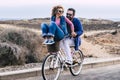 Young playful adult couple man and woman have fun together in outdoor leisure activity riding a single bike and laughing a lot - Royalty Free Stock Photo