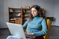 Young pleasant woman in headset using laptop talking with partner via video chat from home Royalty Free Stock Photo