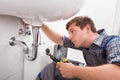 Young plumber fixing a sink in bathroom Royalty Free Stock Photo