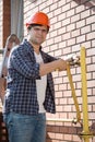 Young plumber in hardhat maintaining yellow gas pipes outside of