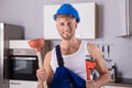 Young Plumber Holding Wrench And Plunger In Kitchen Royalty Free Stock Photo