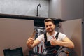 A young plumber holds a wrench in his hand and smiles at the camera on the background of the kitchen