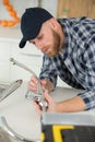 young plumber installing tap in kitchen Royalty Free Stock Photo