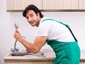 Young plumber repairing tap at kitchen Royalty Free Stock Photo