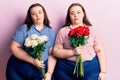 Young plus size twins holding flowers thinking attitude and sober expression looking self confident