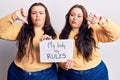 Young plus size twins holding my body my rules banner with angry face, negative sign showing dislike with thumbs down, rejection