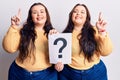 Young plus size twins holding question mark surprised with an idea or question pointing finger with happy face, number one Royalty Free Stock Photo