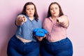 Young plus size twins holding vintage telephone pointing with finger to the camera and to you, confident gesture looking serious Royalty Free Stock Photo